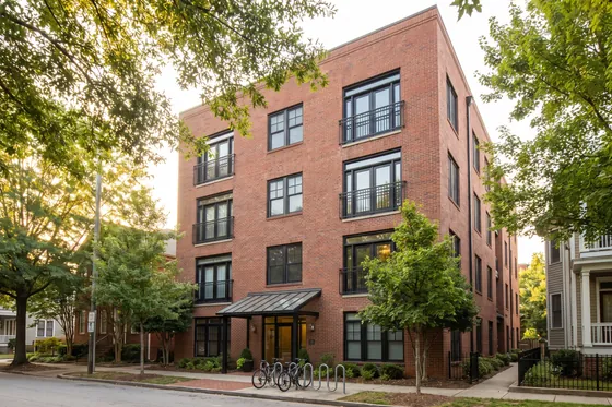 A four-storey brick condominium building with black-framed windows and juliet balconies